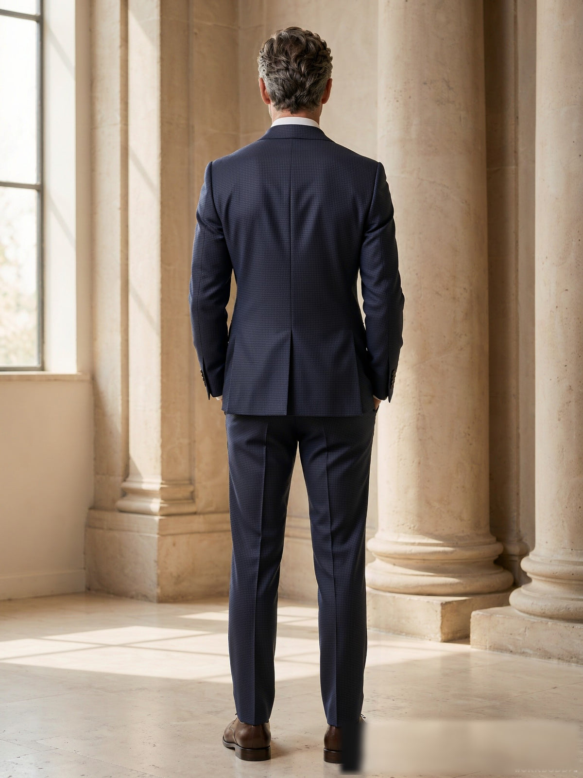 Mature model wearing a tailored navy birdseye Drago wool two-piece suit - back view