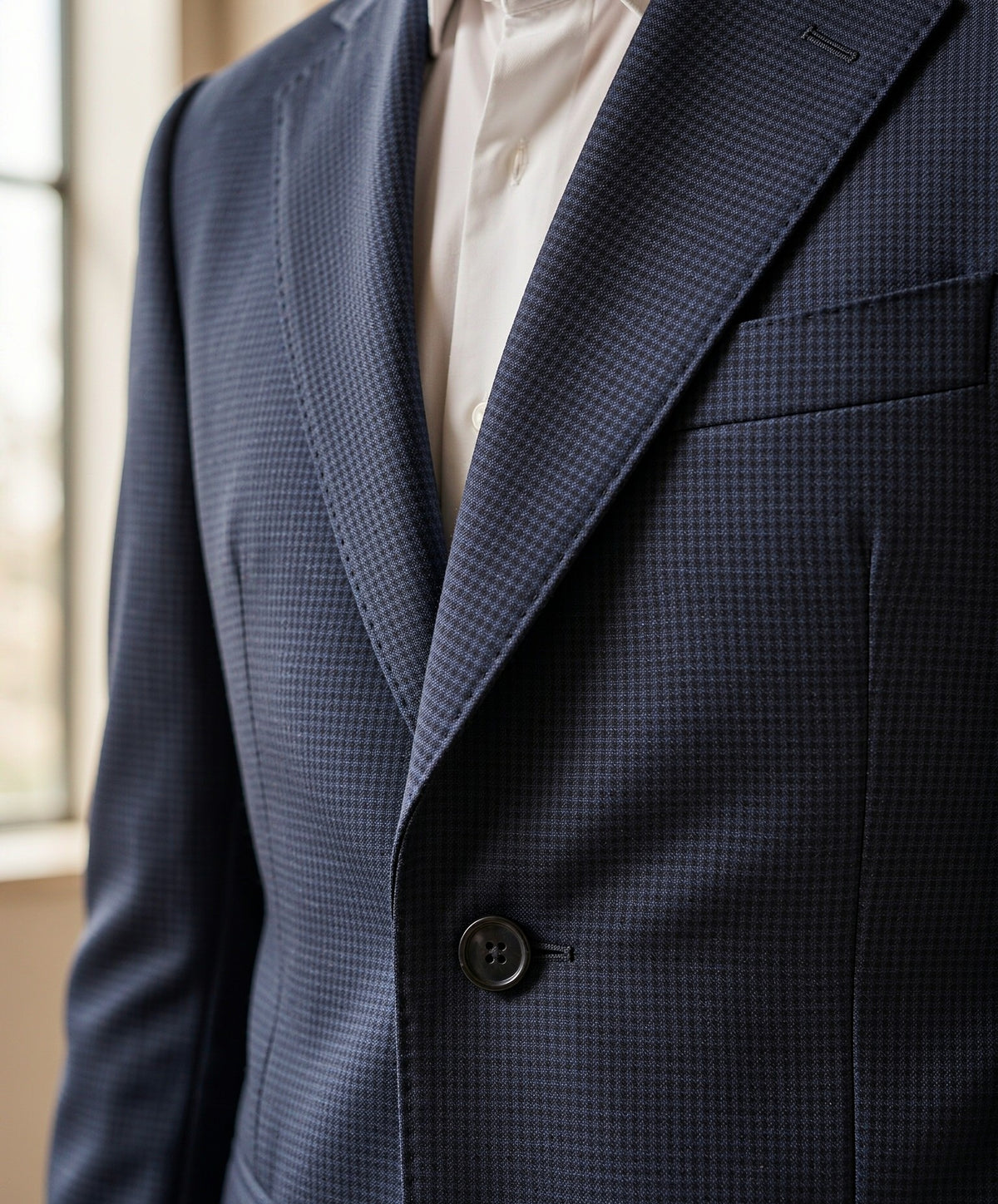 Close-up detail of navy birdseye Drago wool suiting cloth - lapel, button and weave