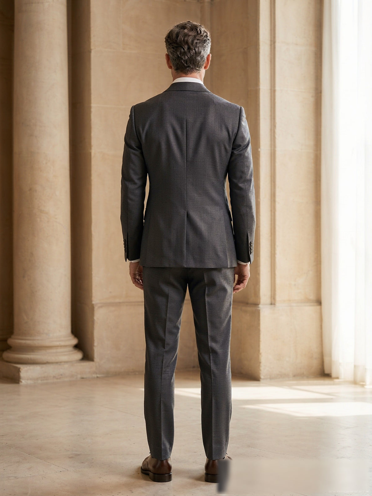 Mature model wearing a tailored charcoal grey Drago wool two-piece suit - back view