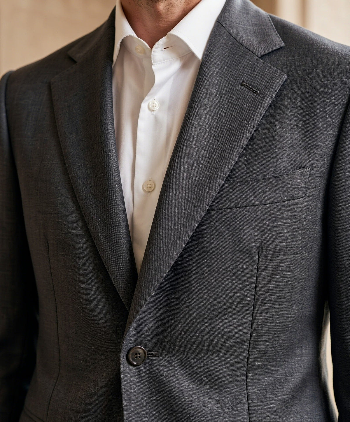 Close-up detail of charcoal grey Drago wool suiting cloth - notch lapel, button and weave