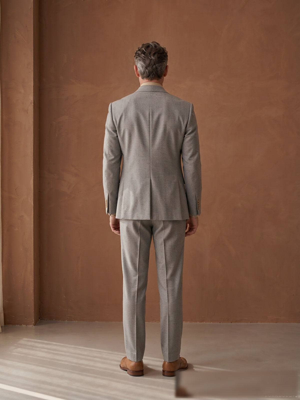Mature model wearing a tailored grey Guabello wool double-breasted suit - back view
