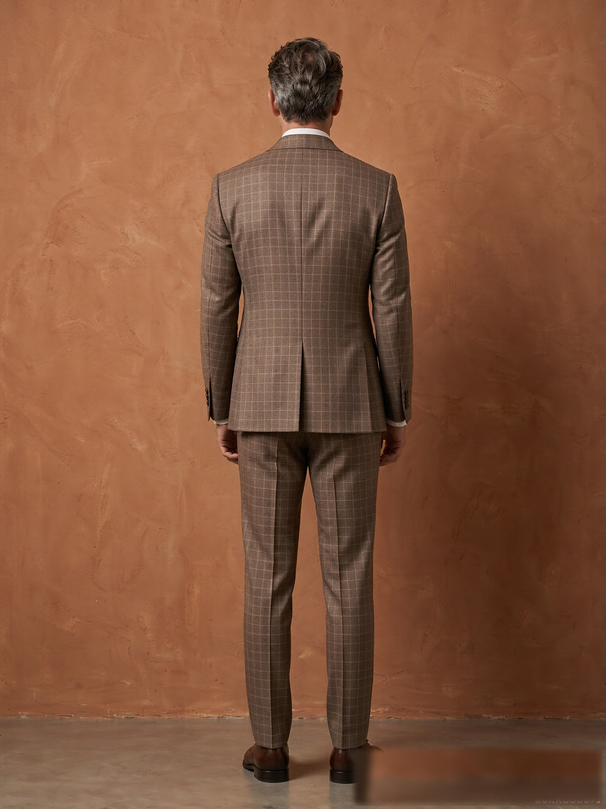 Mature model wearing a tailored brown plaid Guabello wool double-breasted suit - back view