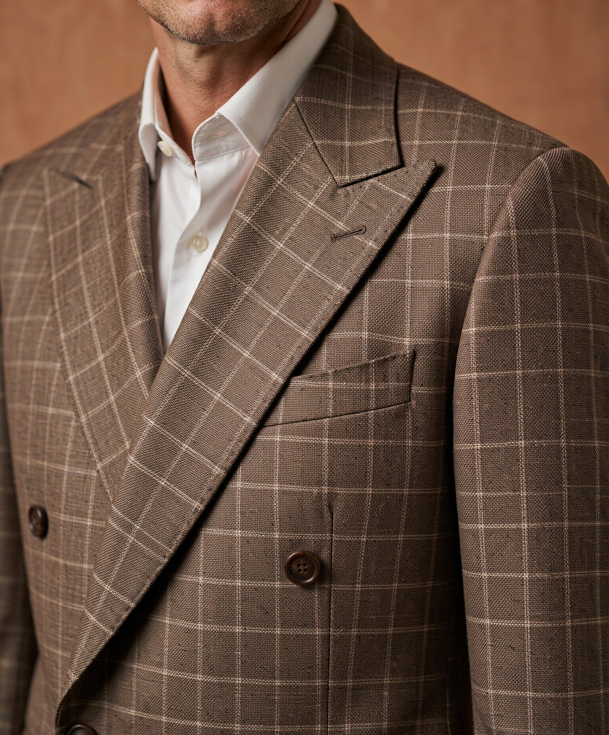Close-up detail of brown plaid Guabello wool suiting cloth - lapel, button and weave