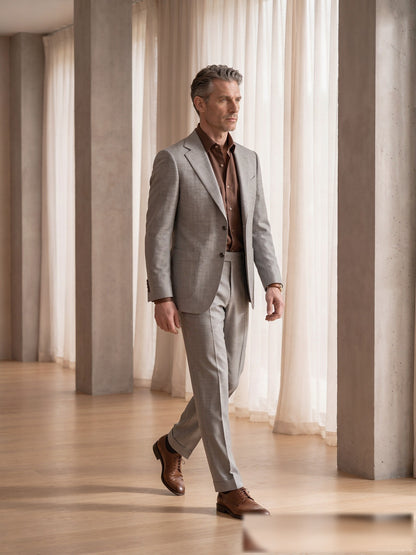Mature model wearing a tailored light-grey VBC wool two-piece suit with brown shirt - side view
