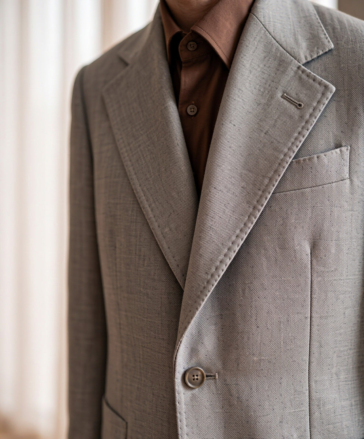 Close-up detail of light-grey VBC wool suiting cloth - lapel, button and fabric weave