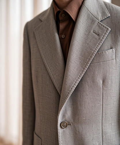 Close-up detail of light-grey VBC wool suiting cloth - lapel, button and fabric weave