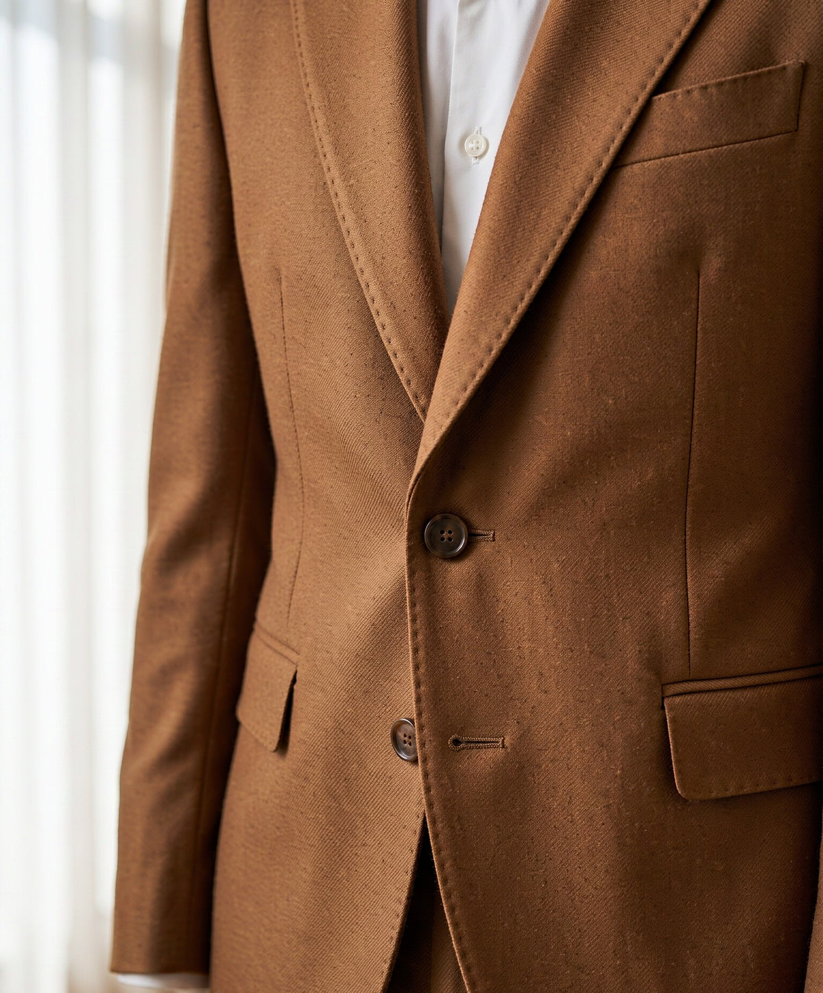 Close-up detail of warm beige VBC wool suiting cloth - lapel, button and fabric weave